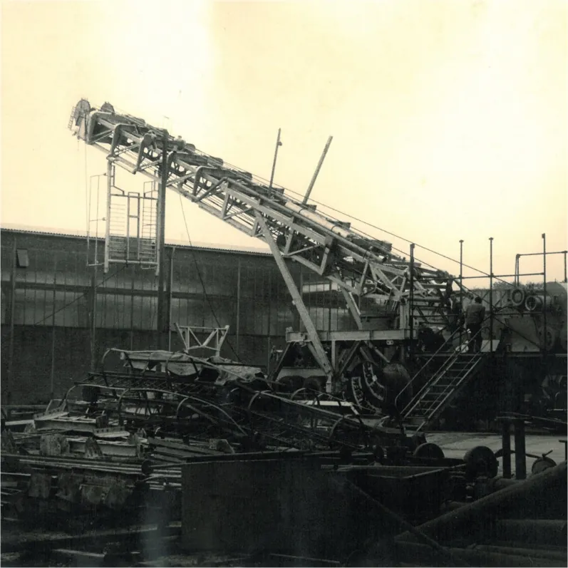 Historic black-and-white photograph of an early drilling rig at a manufacturing yard, linked to Enmiova and Emnicuo heritage and EXUOCOVA branding.